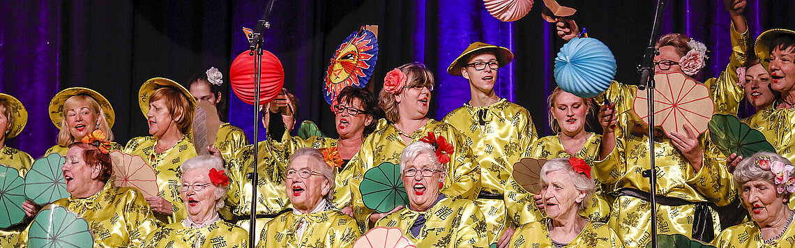 Bewohner der Quartiere singen im Chor auf einer Bühne vor Publikum